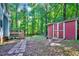 View of a spacious backyard featuring a shed, a stone pathway, mature trees, and access to a deck at 838 Joyner Ct, Wake Forest, NC 27587