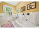 Bright bathroom with a large tub, tiled walls, a large window with shutters, and a vintage sink at 1004 E Willowbrook Dr, Burlington, NC 27215