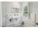 Bathroom with white tiled walls, a large window with shutters, and a vintage sink at 1004 E Willowbrook Dr, Burlington, NC 27215