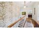 Upstairs hallway showcasing wallpaper, hardwood floors, and a view into a bedroom at 1004 E Willowbrook Dr, Burlington, NC 27215