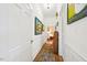 Hallway featuring neutral walls, artwork, and hardwood floors with a decorative rug leading to a bedroom at 1004 E Willowbrook Dr, Burlington, NC 27215