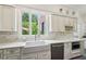 Modern kitchen features bright white cabinetry, stainless appliances, and a view to the backyard at 1004 E Willowbrook Dr, Burlington, NC 27215