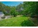 Image shows a backyard with mature trees, green grass, and a pool at 1005 Hidden River Ct, Raleigh, NC 27614