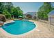 Beautiful in-ground pool with lush green surroundings and back view of the home with an outdoor dining space at 1005 Hidden River Ct, Raleigh, NC 27614