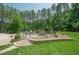 A stone stair path leading up to an in-ground pool with slide, umbrella seating, and lush forestry at 1005 Hidden River Ct, Raleigh, NC 27614