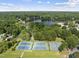 Aerial photo highlighting community amenities; tennis courts with a lake and houses in a lush, tree-filled landscape at 107 Wimbledon Ct, Cary, NC 27511