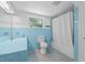 Retro blue bathroom with tiled walls, sink, toilet, bathtub, and window at 1090 S Fifth St, Mebane, NC 27302