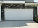 The two-car garage features a white door and stone accents at 1116 Sidney Creek Dr # 1116, Zebulon, NC 27597