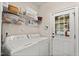 Functional laundry room featuring a washer, dryer, storage shelving, and an exterior door at 121 Fort Jackson Rd, Morrisville, NC 27560