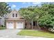 Charming brick and siding home with a two-car garage, lush lawn, and mature flowering tree at 1211 E Pointe Dr, Durham, NC 27712