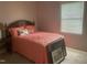 Bedroom features a cozy bed with pink bedding, side table with lamp, and lots of light at 1913 Rendall St, Burlington, NC 27215