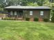 Traditional single-story house with a dark exterior and manicured green bushes, offering cozy curb appeal at 1913 Rendall St, Burlington, NC 27215