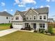 Inviting two-story home with a charming front porch, well-manicured lawn, and attached two-car garage at 200 Cloud Berry Ln, Holly Springs, NC 27540