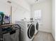 Laundry room with modern appliances, shelving, and tile flooring at 200 Cloud Berry Ln, Holly Springs, NC 27540