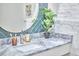 Close up of a bathroom vanity with a marble countertop, round mirror, and blue tile backsplash at 2031 Englewood Ave, Durham, NC 27705