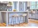 Kitchen island with marble countertop, gray cabinets, two stools, and a view of the sink and window at 2031 Englewood Ave, Durham, NC 27705