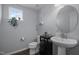 Charming powder room featuring a pedestal sink, decorative mirror, and natural light at 204 Ashland Hill Dr, Holly Springs, NC 27540