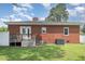 View of the backyard featuring a brick house with a small deck and green lawn at 208 S College Ave, Kenly, NC 27542