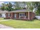 Classic brick home featuring a well-kept lawn, quaint front porch with rocking chairs, and appealing architectural details at 208 S College Ave, Kenly, NC 27542