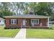 Charming single-story brick home featuring a manicured lawn, front porch with rocking chairs, and inviting curb appeal at 208 S College Ave, Kenly, NC 27542