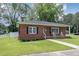 Well-maintained brick home with a lush front lawn, welcoming porch with rocking chairs, and charming curb appeal at 208 S College Ave, Kenly, NC 27542