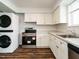 Modern kitchen appliances, including a stacked washer dryer, stove, and white cabinets at 2316 Champion Ct, Raleigh, NC 27606