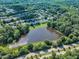 Aerial view of homes nestled among mature trees around a large pond in a residential neighborhood at 240 Meadow Beauty Dr, Apex, NC 27539
