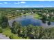 Aerial view of pond featuring a water fountain surrounded by homes and green, mature landscaping at 240 Meadow Beauty Dr, Apex, NC 27539