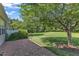 Brick patio in a well-maintained backyard with lush lawn, mature tree, and privacy landscaping at 240 Meadow Beauty Dr, Apex, NC 27539