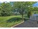 Landscaped backyard featuring a large lawn with a tree, brick patio and a scenic lake view at 240 Meadow Beauty Dr, Apex, NC 27539