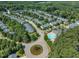 Aerial view of a residential neighborhood with mature trees, a community pool, and a small pond at 240 Meadow Beauty Dr, Apex, NC 27539