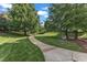 Serene park with a paved walking path, green grass, mature shade trees, and benches at 240 Meadow Beauty Dr, Apex, NC 27539