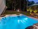 Illuminated hot tub with patio table and chairs, and fire pit in a wooded backyard at 259 Brown Bear, Chapel Hill, NC 27517