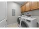 Laundry room with front load washer and dryer and overhead wooden storage cabinets at 260 Easy Wind Ln, Garner, NC 27529