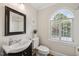 Bright bathroom with a dark vanity, arched window with plantation shutters, and white tile shower and trim at 2725 Rosedale Ave, Raleigh, NC 27607