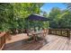Wooden deck features a dining table, umbrella, wrought iron railing, and a peek into the wooded backyard at 2725 Rosedale Ave, Raleigh, NC 27607