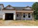 New home under construction features an open garage and covered porch with brick supports against a backdrop of trees at 335 Bluejay St, Clayton, NC 27520