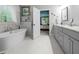 Spacious bathroom with a soaking tub, white tile flooring, double vanity, and an open view of the main bedroom at 3587 Garner Terrace Way, Wake Forest, NC 27587