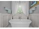 Bright bathroom featuring a soaking tub under a window with white tile flooring and trimmed walls at 3587 Garner Terrace Way, Wake Forest, NC 27587