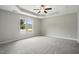 Bright main bedroom featuring a tray ceiling, ceiling fan, neutral paint, large window, and carpeted floors at 39 Blue Heron Ct, Kenly, NC 27542