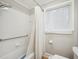 Bathroom featuring a white tiled shower with a grab bar, window, toilet and shower curtain at 3934 Hope Valley Rd, Durham, NC 27707