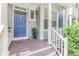 Inviting front porch with a blue door, white columns, and decorative plants at 412 Heritage Village Ln, Apex, NC 27502