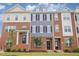 View of three townhomes with brick and gray exteriors, black doors, and manicured lawns on a sunny day at 503 Gateway Townes Blvd, Wake Forest, NC 27587