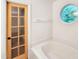 Bright bathroom with a bathtub, round window, and wood-framed glass paneled door at 5105 Carolwood Ln, Durham, NC 27713