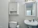 Well-lit bathroom with a classic sink, mirror, storage cabinet, and toilet at 5105 Carolwood Ln, Durham, NC 27713