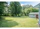 A large, well-manicured backyard with mature trees, a shed, and a neighboring house at 523 Edwards Rd, Henderson, NC 27537