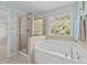 Elegant bathroom featuring a soaking tub, tiled shower, and a large window at 5545 Moneta Ln, Apex, NC 27539