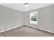 This bedroom features neutral carpet, walls, and trim, along with a window at 567 E Ridge Ave, Liberty, NC 27298
