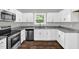 Well-lit kitchen with white cabinets, stainless steel appliances, and granite countertops at 567 E Ridge Ave, Liberty, NC 27298