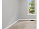 Bright bedroom features neutral carpet, gray walls, white trim, and a window overlooking a green backyard at 6009 Shadow Moss Cir, Raleigh, NC 27603